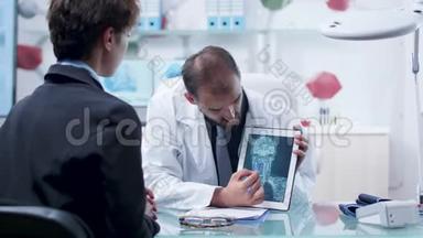 现代研究机构的医生在平板电脑上向病人显示X射线扫描